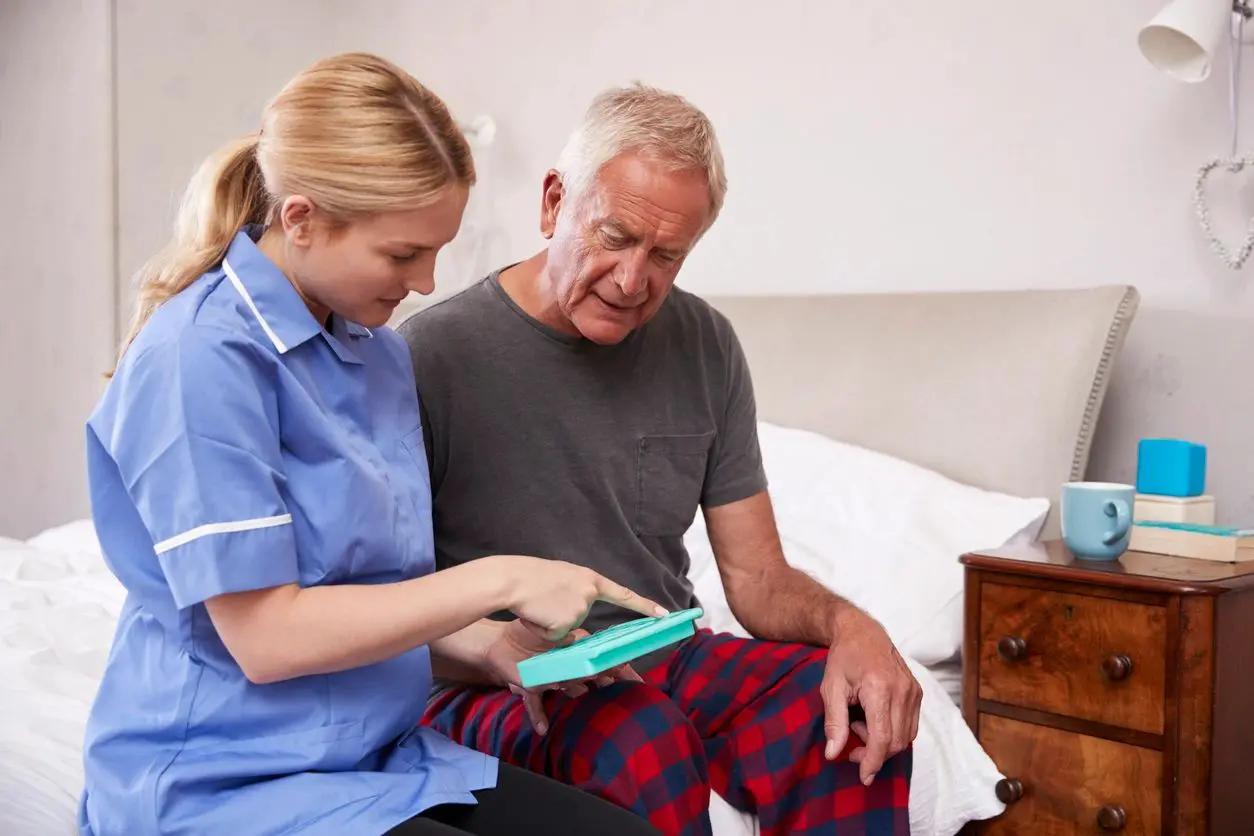 Nurse Helping Senior Man To Organize Medication On Home Visit